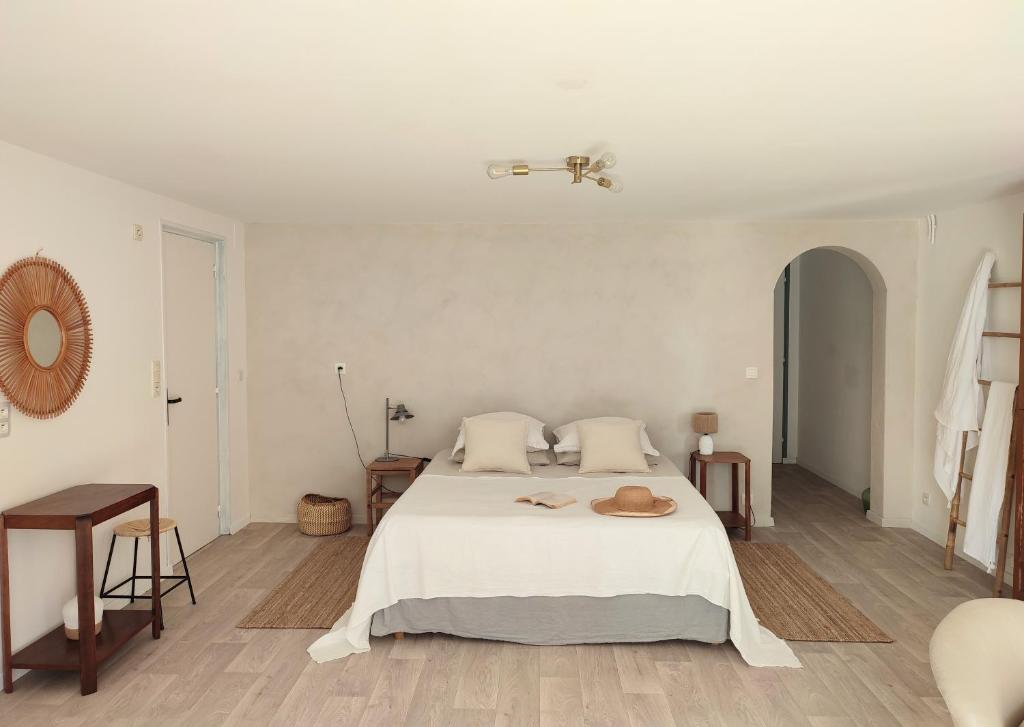 a white bedroom with a bed with a hat on it at Maison Caiada in Urrugne