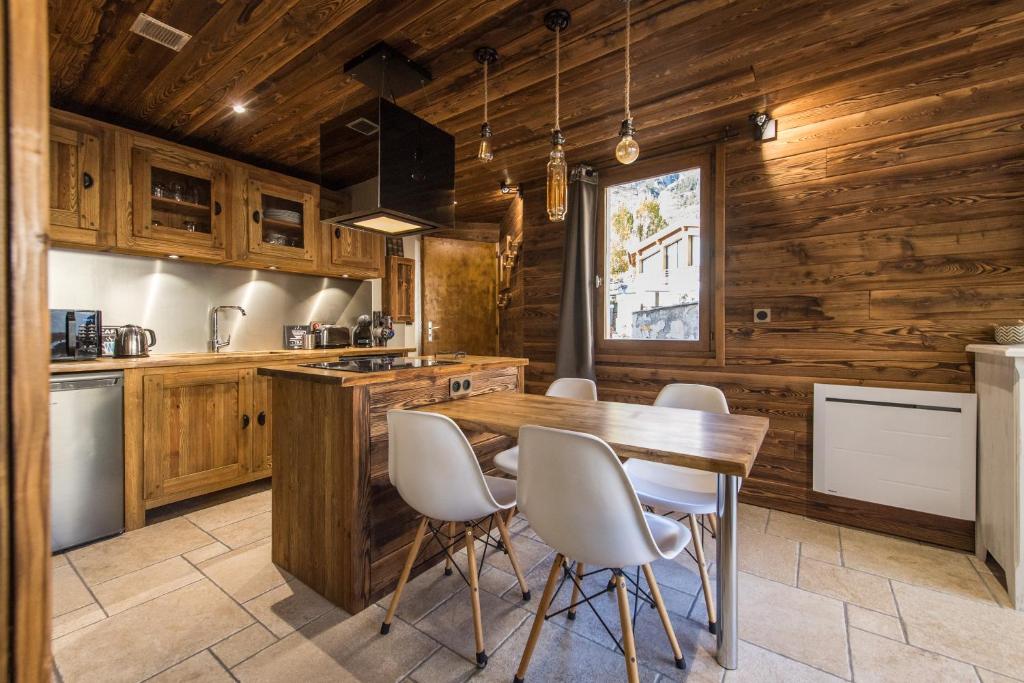 cocina con paredes de madera, mesa de madera y sillas en Norberts Place, en Lanslevillard
