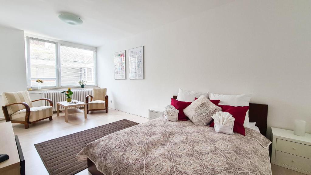a white bedroom with a large bed with red pillows at Premium Buda Castle Apartment in Budapest