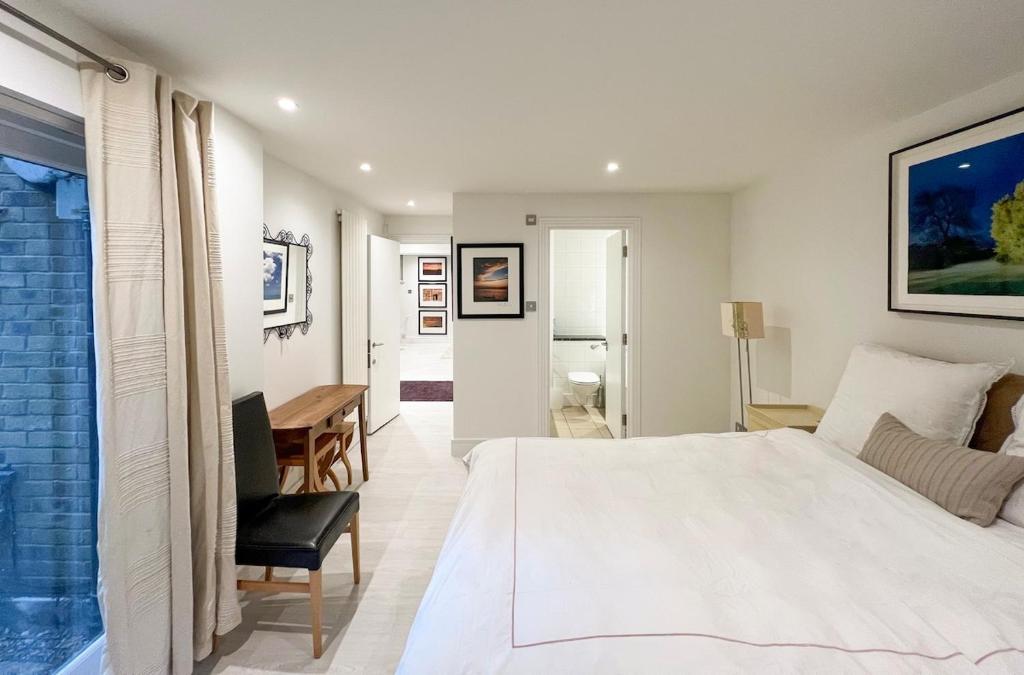 1 dormitorio con 1 cama blanca grande y escritorio en Discounted Two Bed Apartment In The Heart Of Soho, en Londres