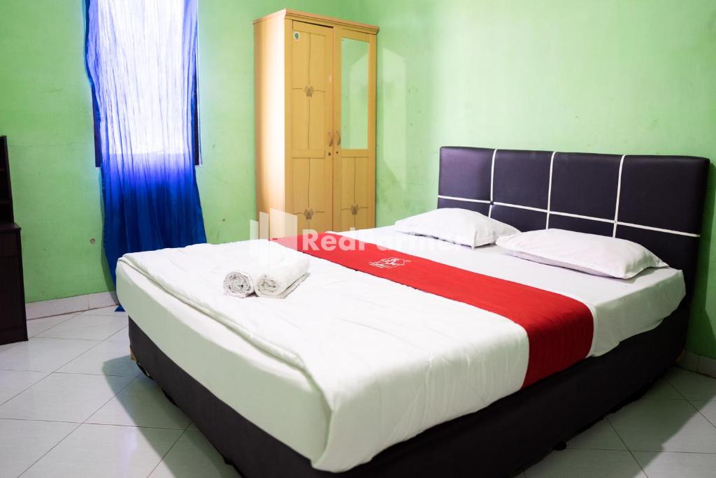 uma cama grande com um cobertor vermelho e branco em Hotel Ratu Ayu 2 Lampung Mitra RedDoorz em Tanjungkarang