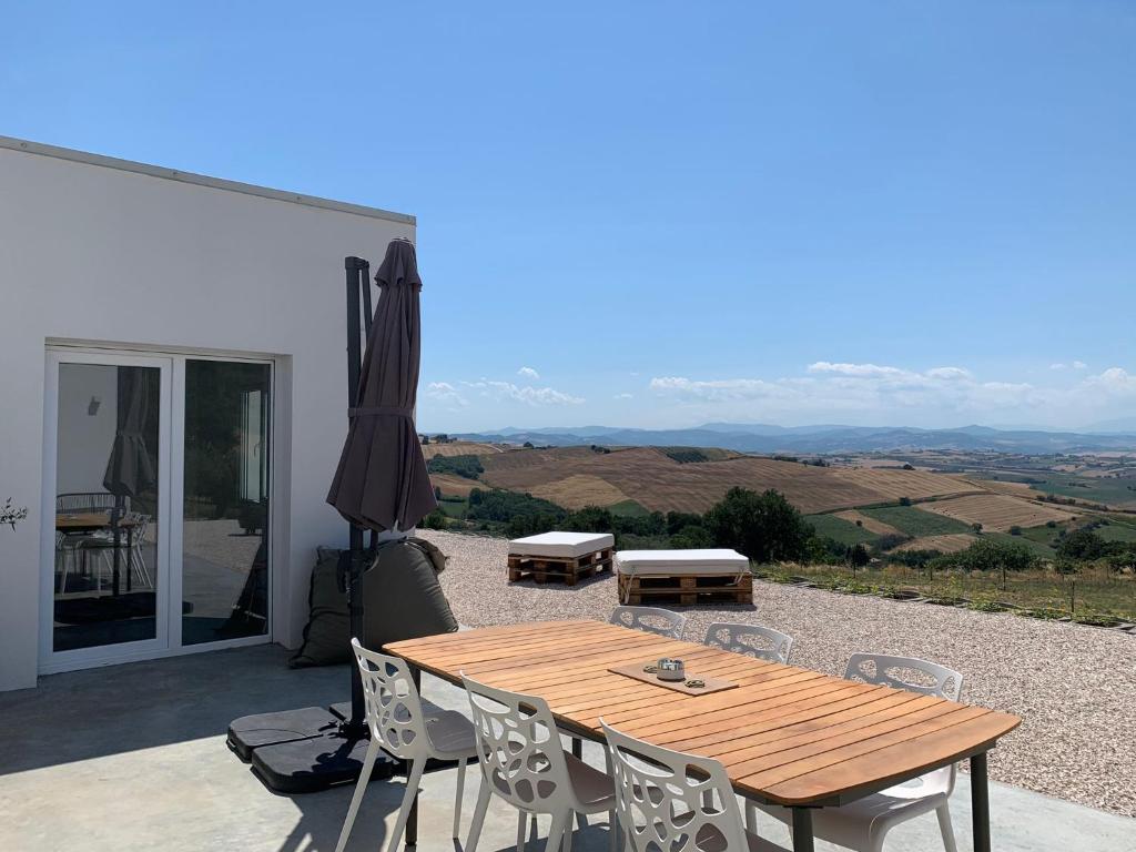 - une table en bois avec des chaises et un parasol sur la terrasse dans l'établissement Casa Al Fianco - Brand new house with a breathtaking view, à Petacciato