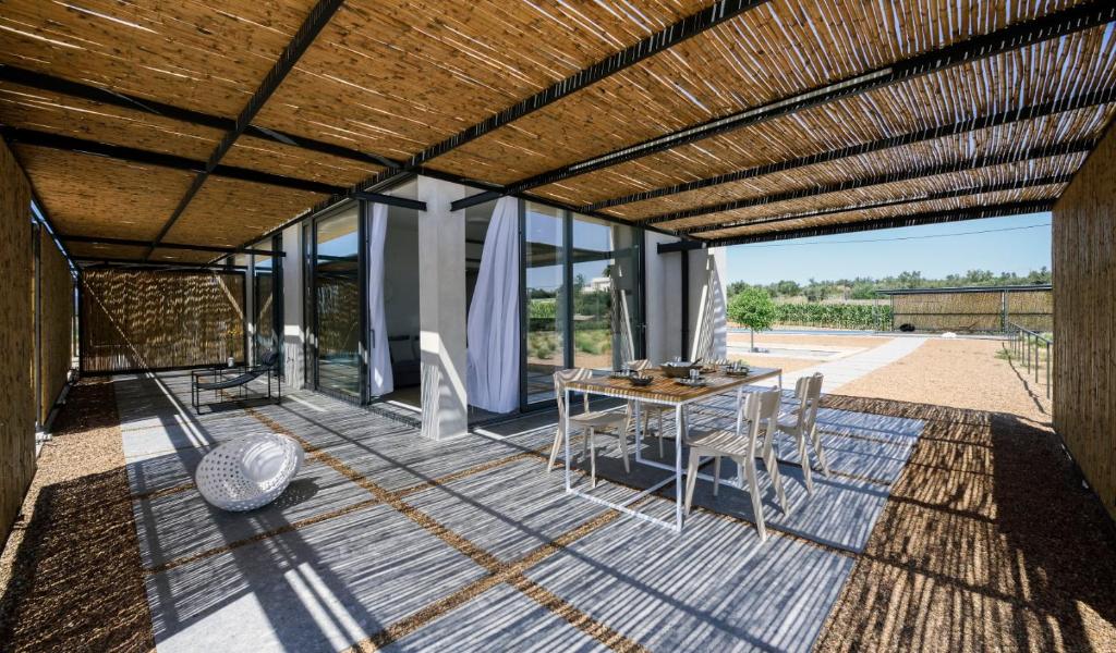 a patio with a table and chairs and windows at Bouca Houses in Messini