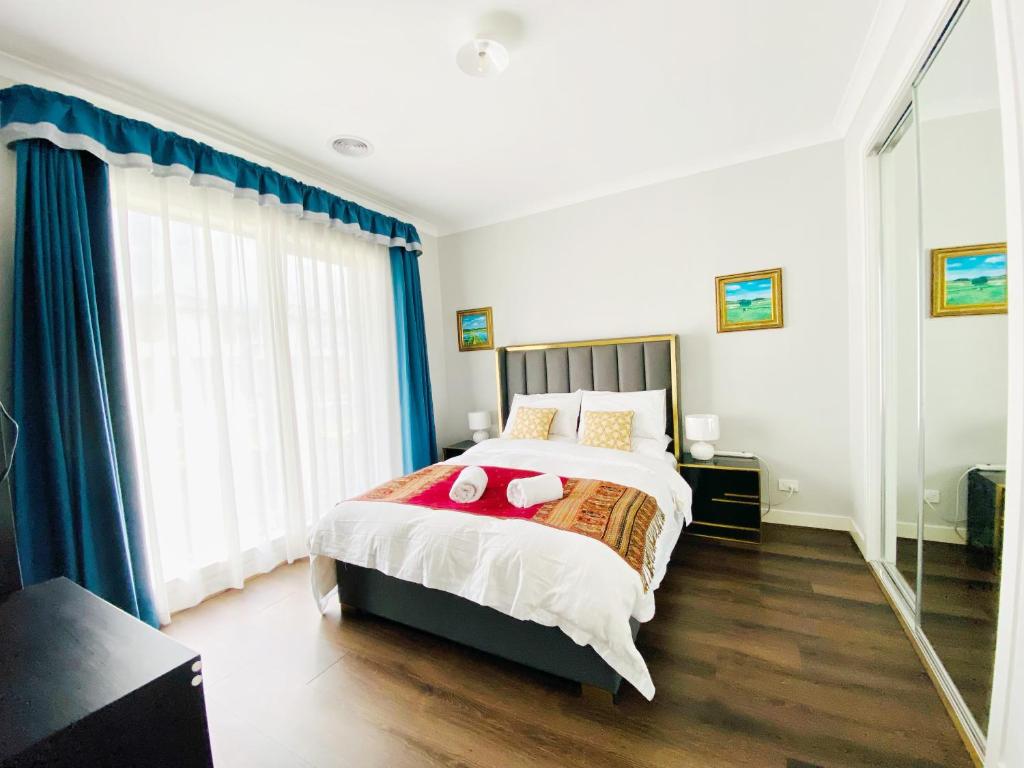a bedroom with a large bed with blue curtains at DnF House in Williams Landing in Laverton