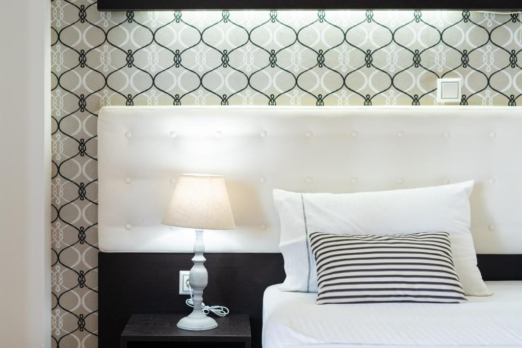 a bedroom with a white bed with a black and white headboard at 3Aktes Suites & Studios in Syvota