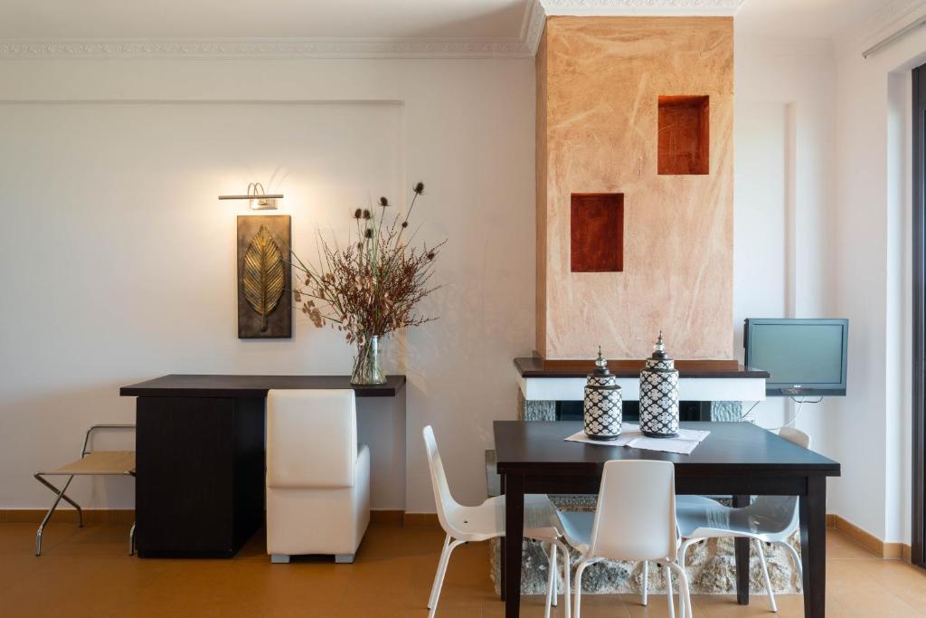 a dining room with a black table and white chairs at 3Aktes Suites & Studios in Syvota