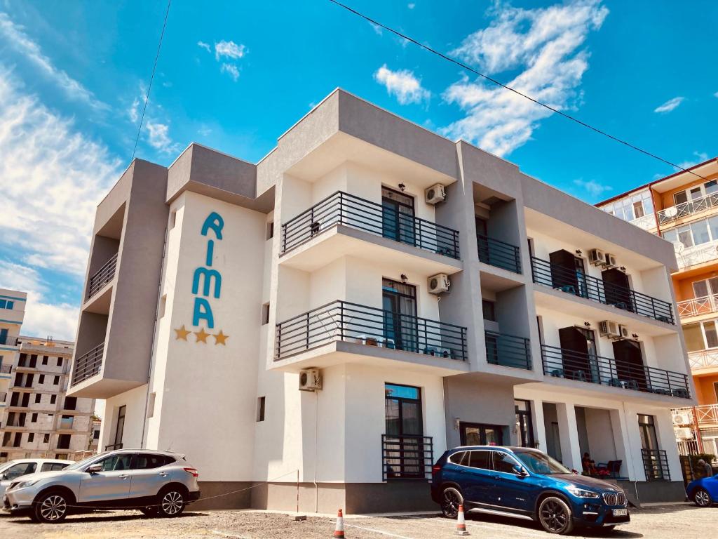 a white building with cars parked in front of it at RIMA Del Mar in Eforie Nord