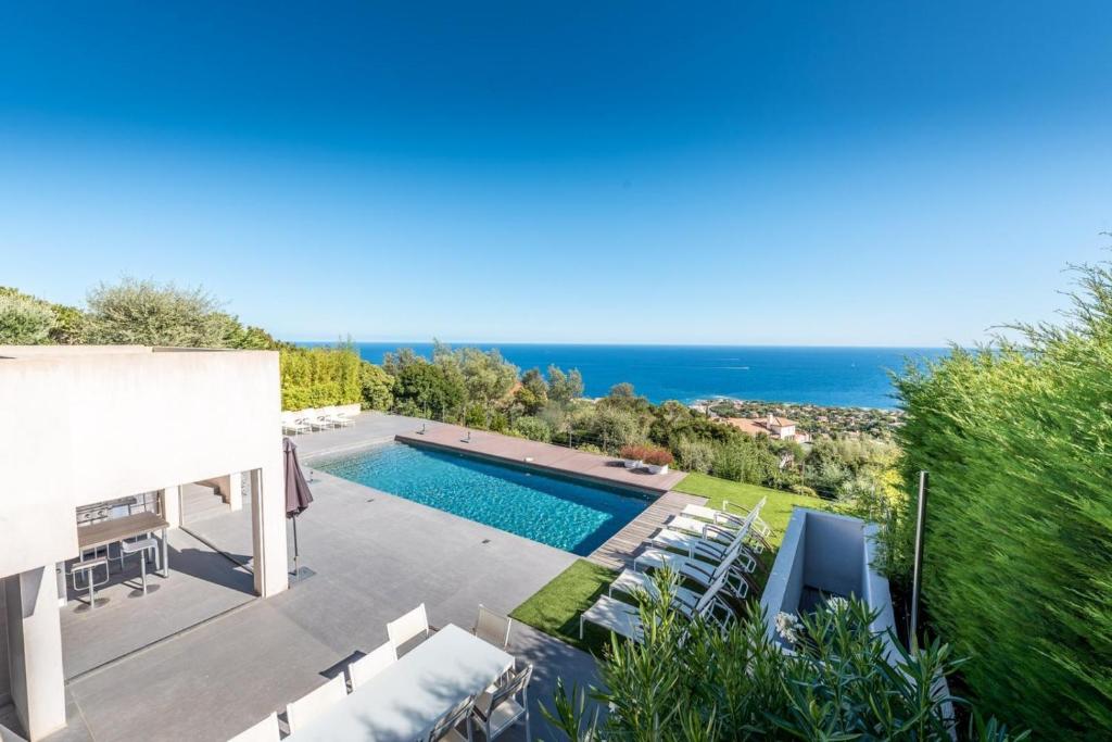 a villa with a swimming pool and the ocean at Vue panoramique sur la baie de St Tropez in Les Issambres