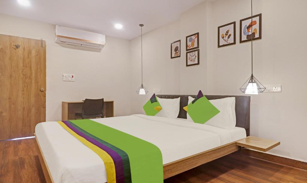 a bedroom with a large white bed with green accents at Treebo Trend Seventh Heaven Kukatpally in Hyderabad
