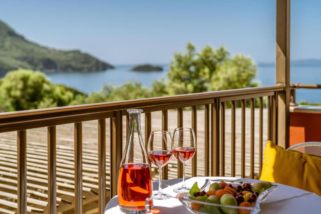 a table with two glasses of wine and a bowl of fruit at 3Aktes Suites & Studios in Syvota
