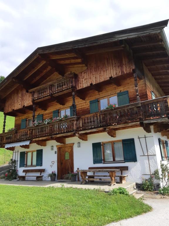 Cette grande maison en bois possède un balcon. dans l'établissement Ferienwohnung Schatzhof, à Jochberg