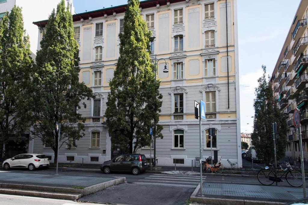 duży biały budynek z samochodami zaparkowanymi przed nim w obiekcie YouHosty - Pavia 7 w Mediolanie