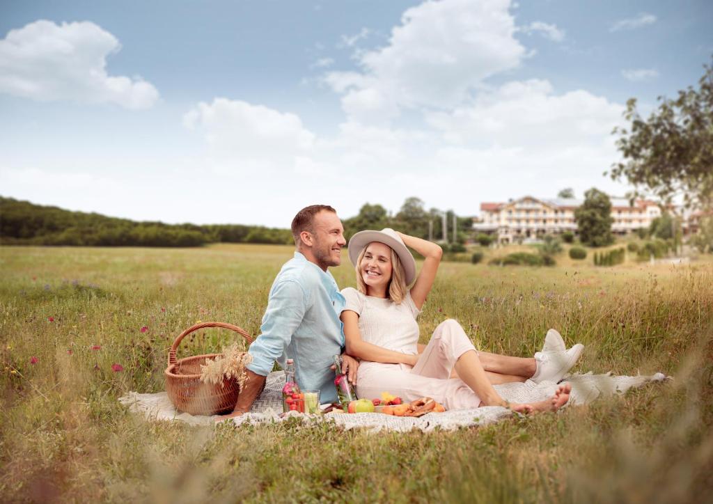 a man and a woman sitting on a blanket in a field at Wellness Natur Resort Gut Edermann in Teisendorf