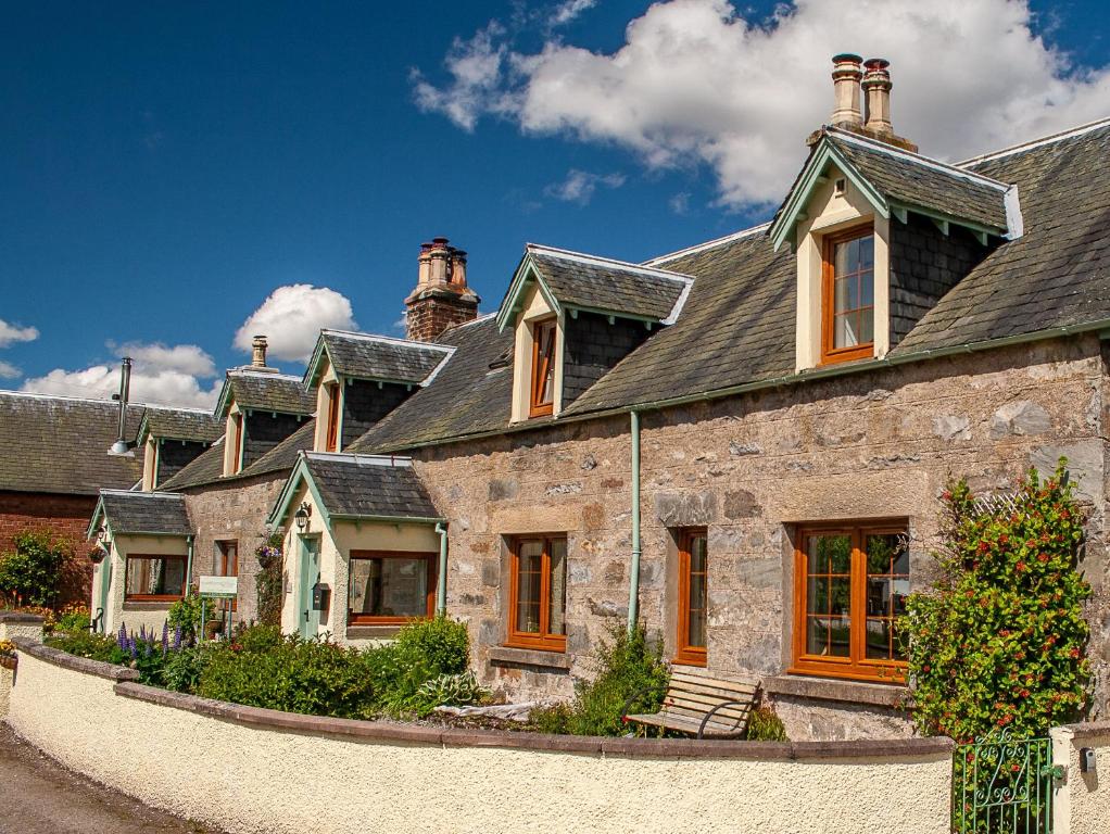een groot stenen huis met een dak bij Rosemount Cottage ONE- Highland Cottage in Garve