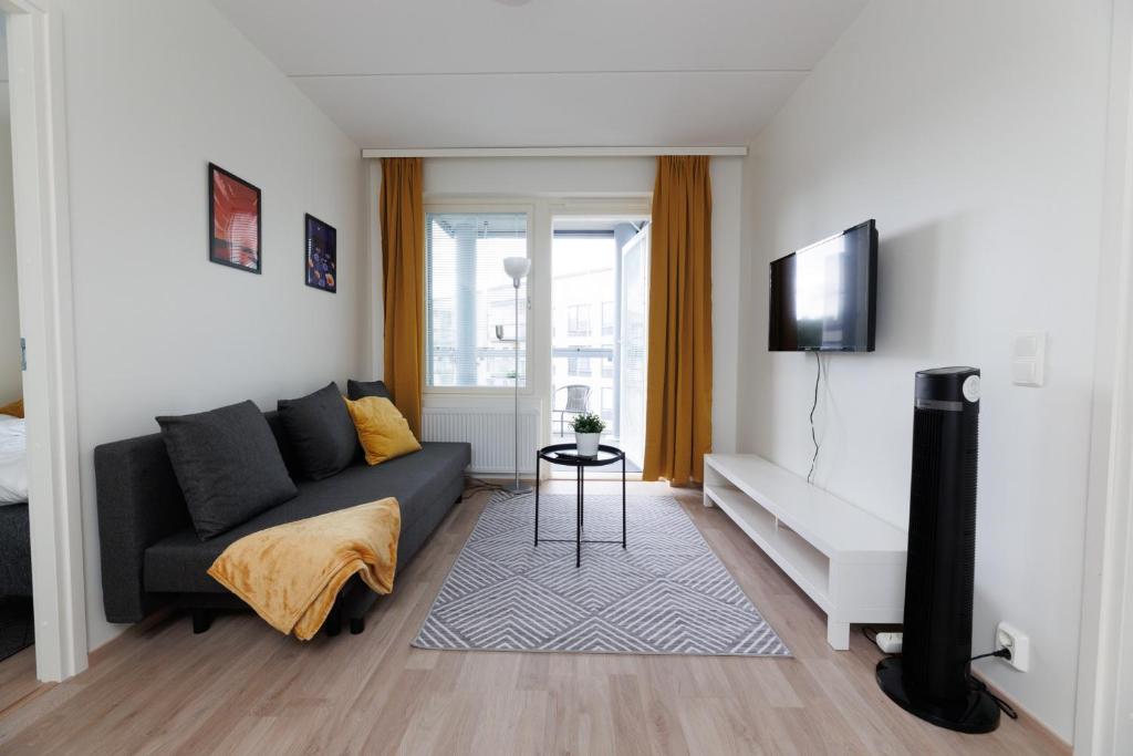 a living room with a couch and a tv at Hiisi Homes Hämeenlinna Asemanranta in Hämeenlinna