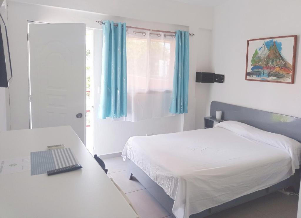 a bedroom with a bed and a desk with a laptop at Hotel Casa Coco in Boca Chica