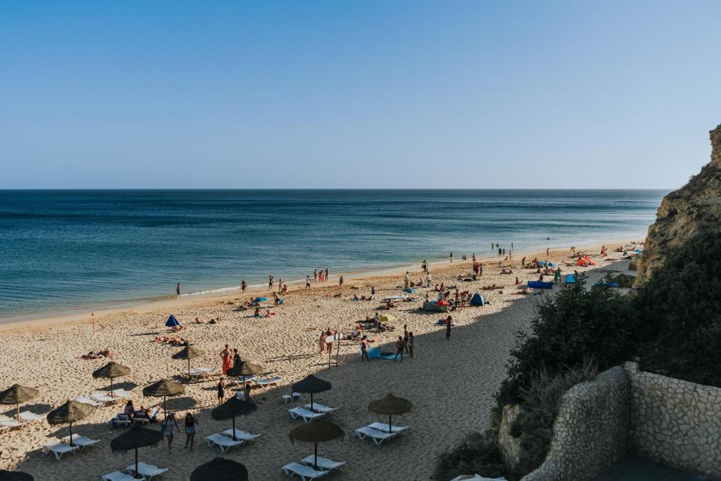 a group of people on a beach with umbrellas at Casa Praia Mar in Salema