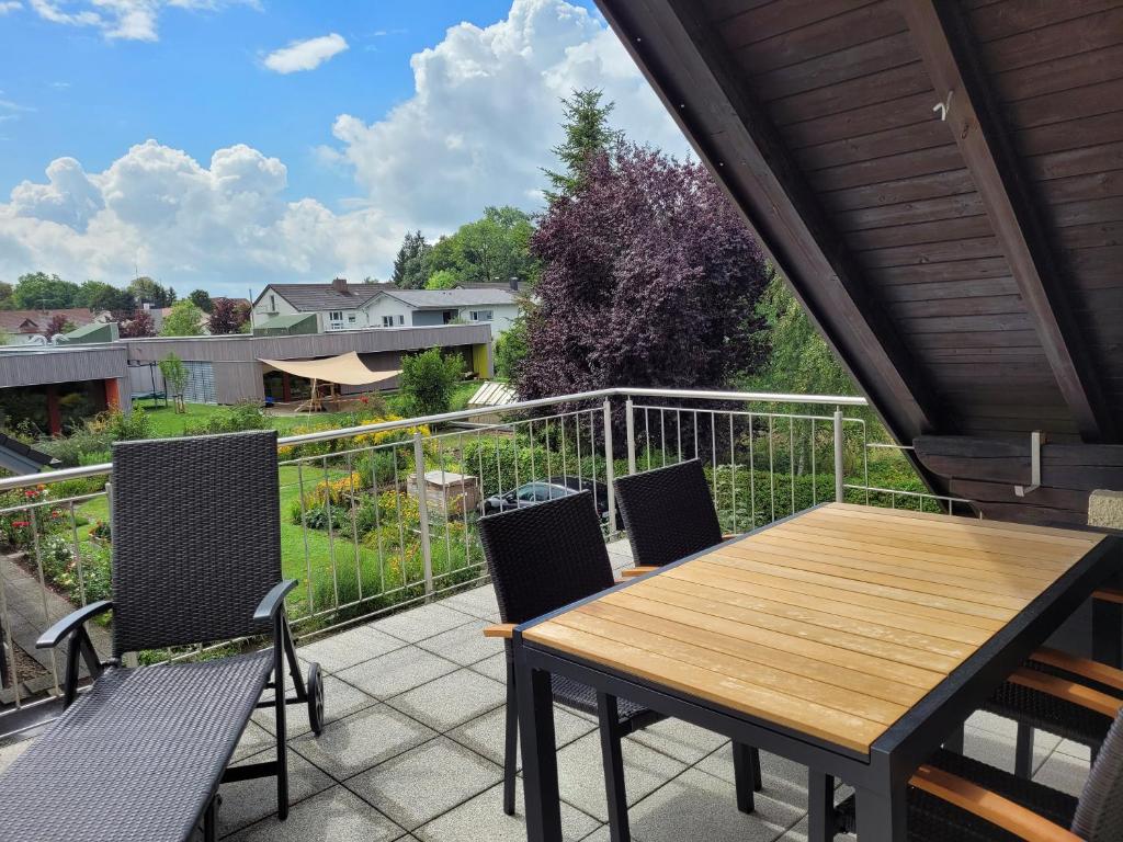patio con mesa de madera y sillas en el balcón en Ferienwohnung Allgäu en Kißlegg