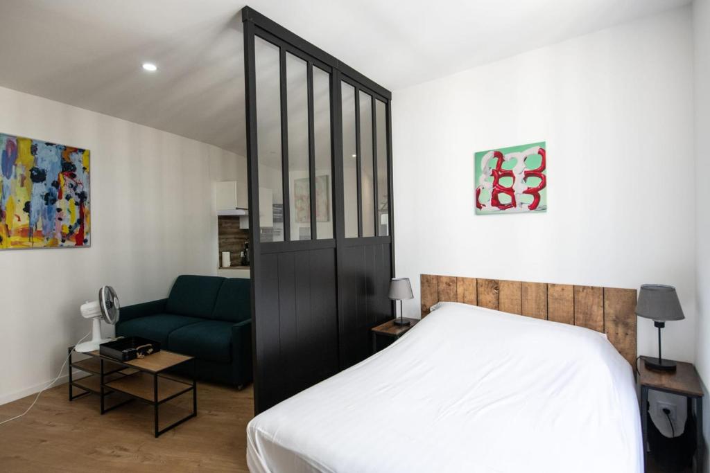 a bedroom with a bed and a blue couch at L'Arty - Très joli studio moderne place Valmy in Lyon