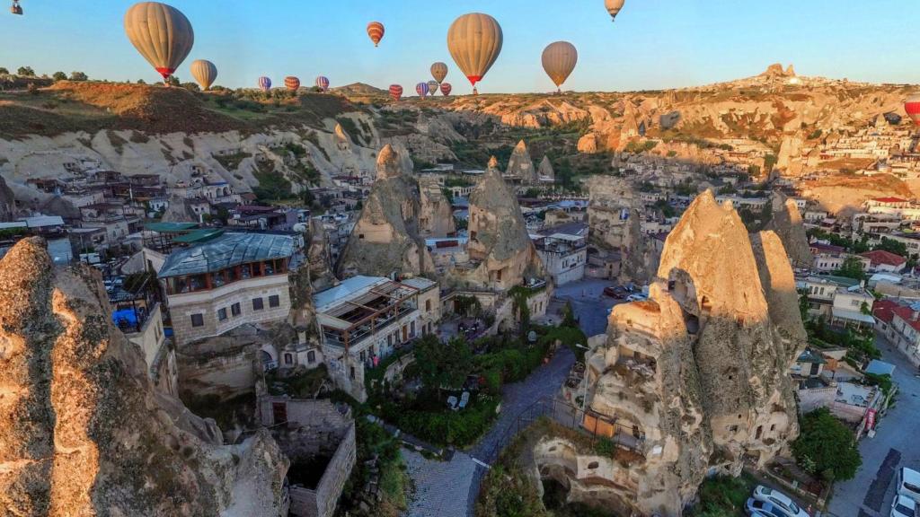 um grupo de balões de ar quente sobrevoando uma cidade em Amber Cave Suites em Goreme