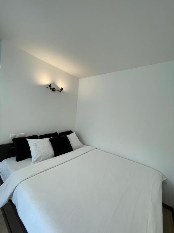 a white bed with black pillows in a room at Studio apartment in Valmiera