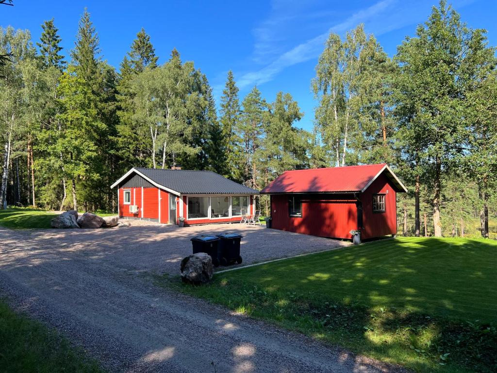 eine rote Hütte im Wald mit Auffahrt in der Unterkunft Asserbostugan in Överlida