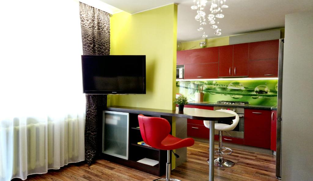 a kitchen with red cabinets and a table with red chairs at M&M Apartment II SELF CHECK-IN in Panevėžys