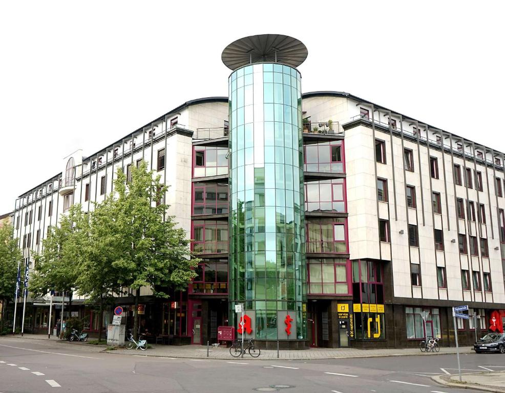 a building with a glass tower in front of a street at Dorint Hotel Leipzig in Leipzig