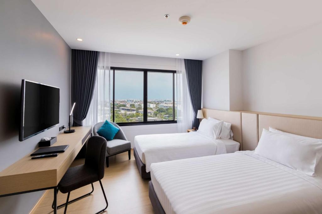 A twin room with a clear city-facing window, desk and television.