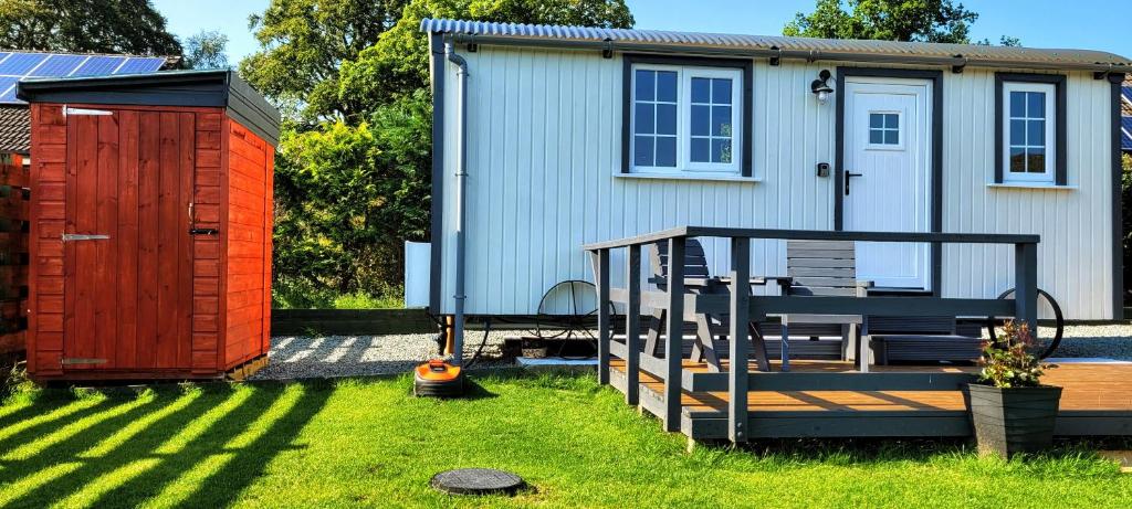 einen Hinterhof mit einem Schuppen, einer Terrasse und einem Haus in der Unterkunft Cozy Shepherd hut 20 by 7 feet with boxed in high double bed in Balmacara