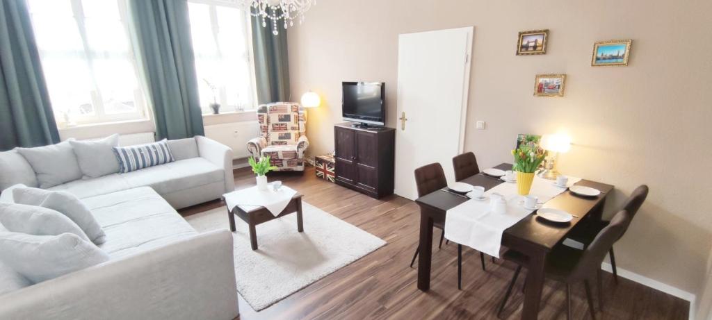 - un salon avec un canapé et une table avec des chaises dans l'établissement Apartment London, à Mühlhausen