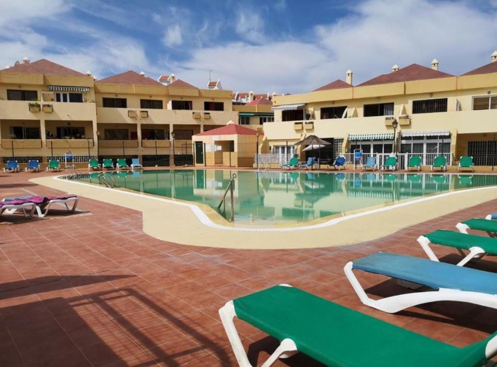 a large swimming pool with green chairs in a resort at Best Holiday Fanabe in Adeje