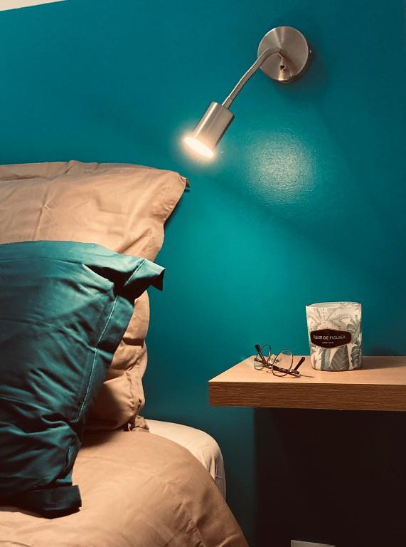 une chambre avec un mur bleu et un lit avec une lampe dans l'établissement Le Flocmagny, à Châlons-en-Champagne