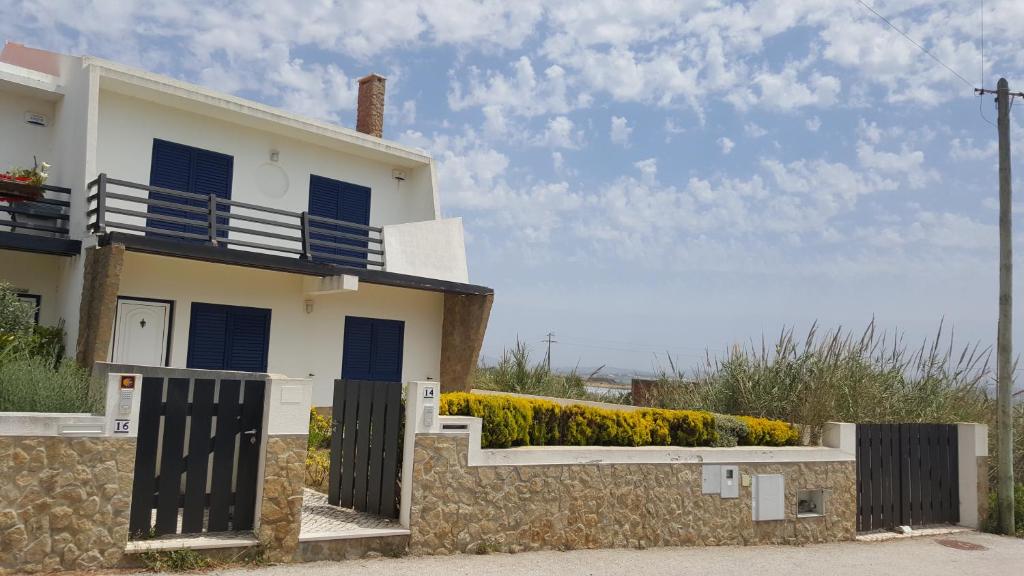 SilveiraにあるVilla da Praia Azulの青いシャッターと石壁の白い家