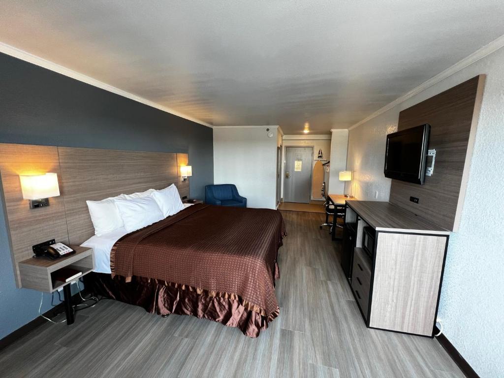 ein Hotelzimmer mit einem Bett und einem Flachbild-TV in der Unterkunft Super 8 by Wyndham Fort Worth Entertainment District in Fort Worth