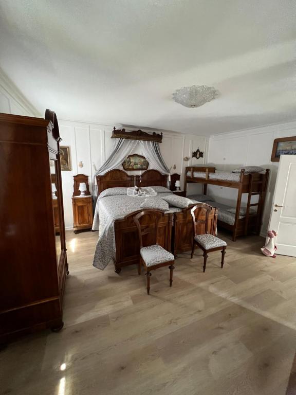 a bedroom with a bed with chairs and a table at Palazzo Cervesato Appartamento: Maria Luisa in Santo Stefano di Cadore