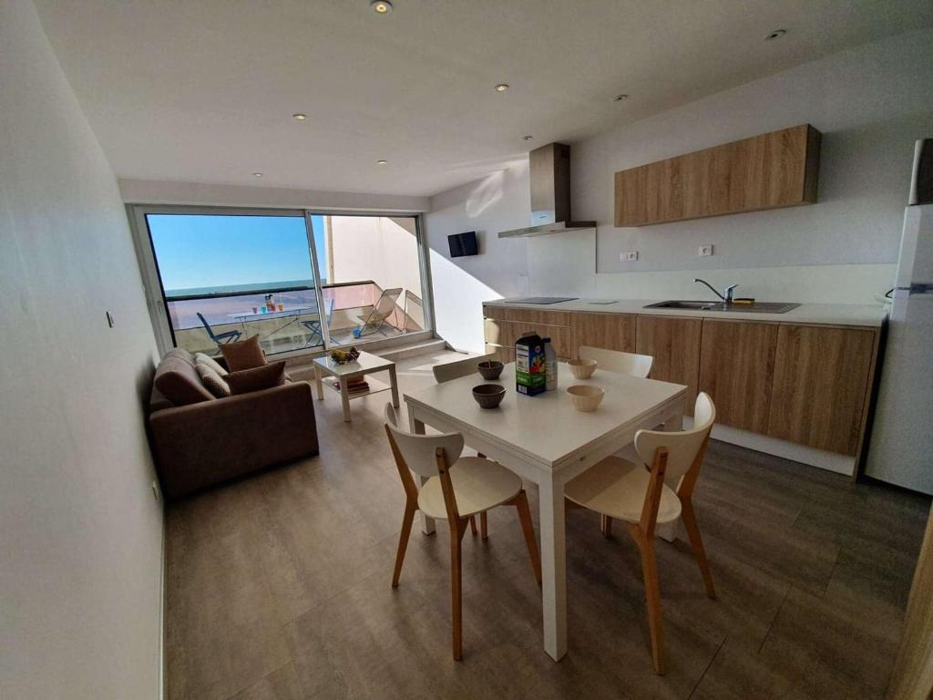 une cuisine et un salon avec une table et des chaises dans l'établissement Studio cabine 4 couchages, Saint-Jean-de-Monts, balcon, parking, à 2 pas de l'océan - FR-1-224C-194, à Saint-Jean-de-Monts