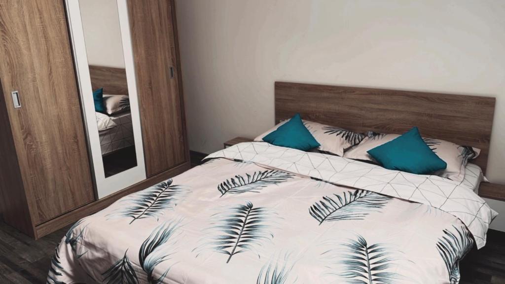 1 dormitorio con cama con almohadas azules y espejo en Apartament cu 2 camere, spatios si confortabil. en Timisoara