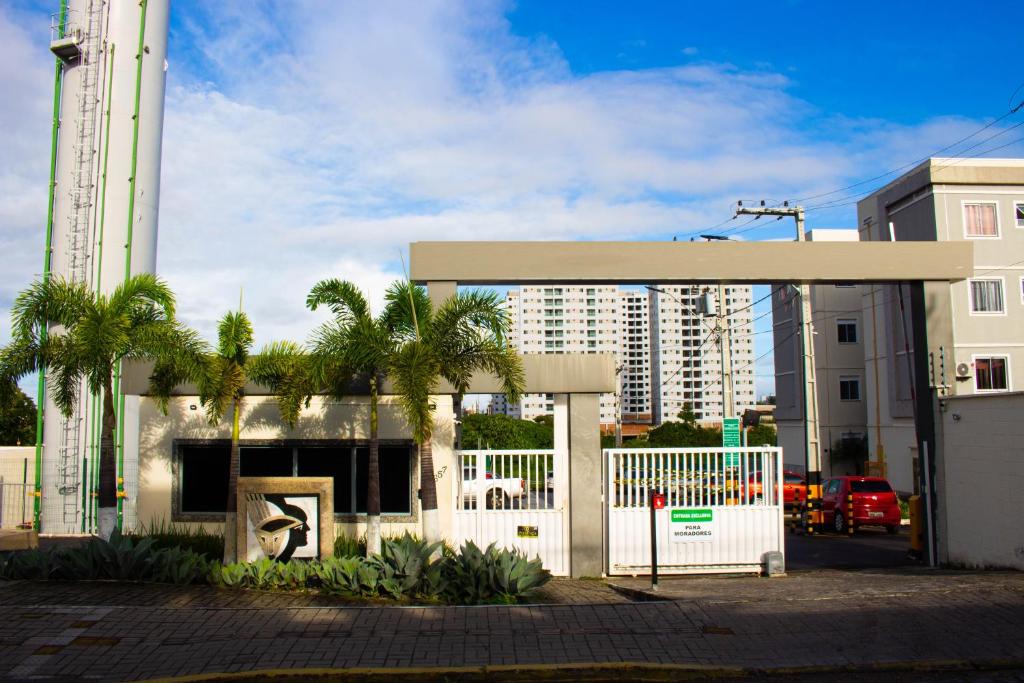 a white building with a white gate and palm trees at Perto do Mar, 5G, Ar e Piscina C/Churrasqueira in João Pessoa
