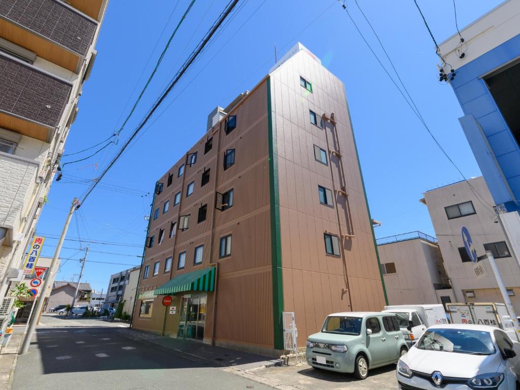 un edificio alto con coches estacionados frente a él en Tabist IWATA Station Hotel en Iwata