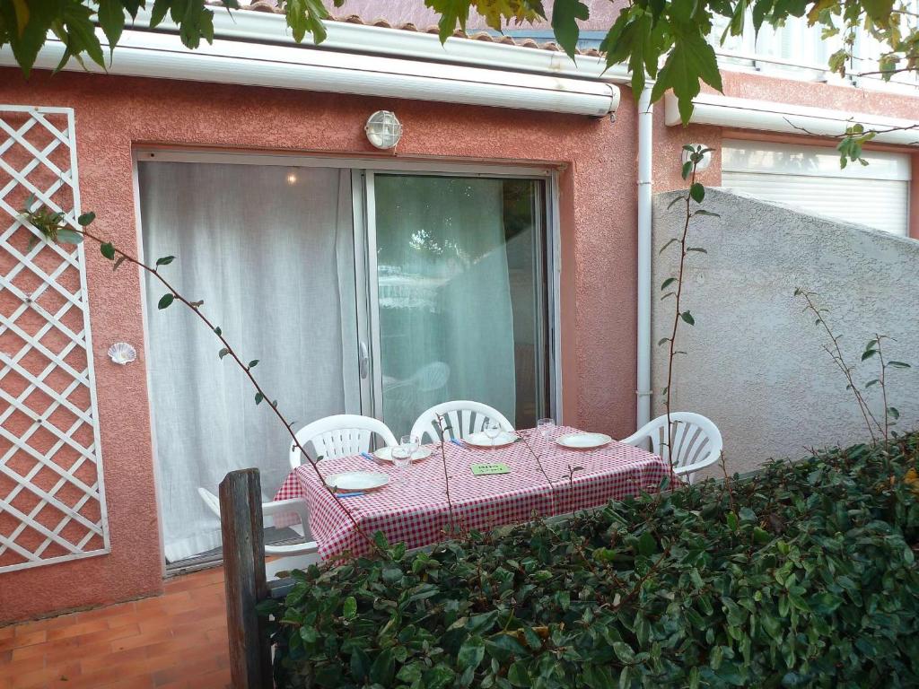 une table et des chaises roses sur une terrasse avec une fenêtre dans l'établissement Maison de vacances au canal, 2 chambres, animaux admis, parking privé - FR-1-387-86, à Marseillan