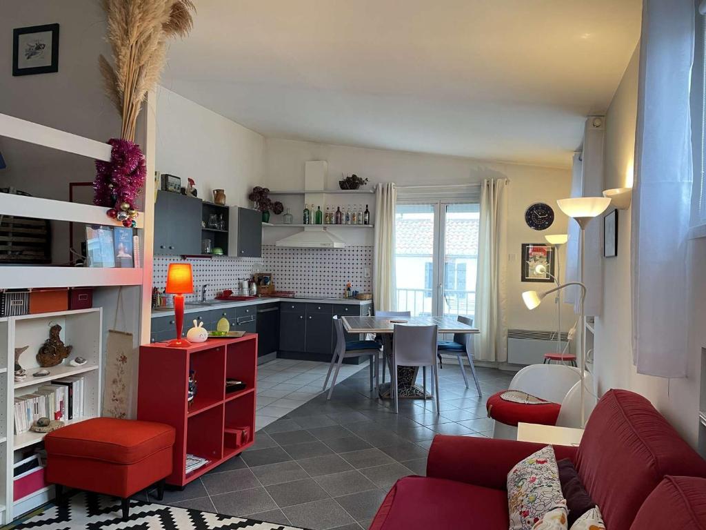 un salon avec un canapé rouge et une cuisine dans l'établissement Bel appartement 3 pièces proche plage des Dames à Noirmoutier - FR-1-224B-179, à Noirmoutier-en-l'lle