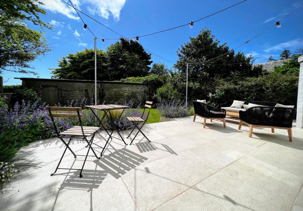 a patio with chairs and a table in a garden at Beautiful Rural Cottage by the Coast in East Portlemouth