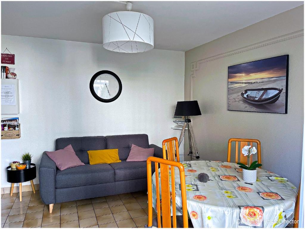 a living room with a couch and a table at Cabourg, Appartement plain pied avec terrasse accès direct à la plage in Cabourg