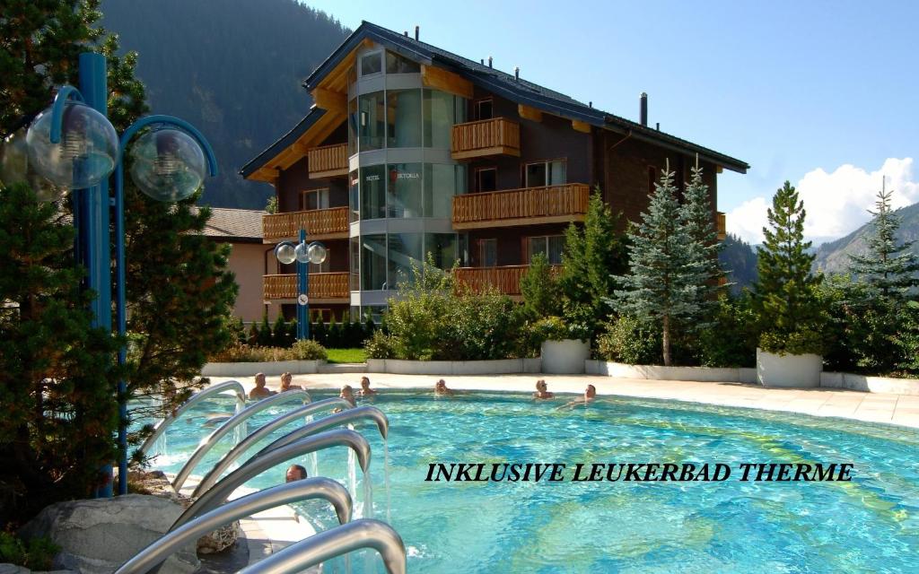 a large swimming pool in front of a hotel at Hotel Viktoria-Leukerbad-Therme in Leukerbad