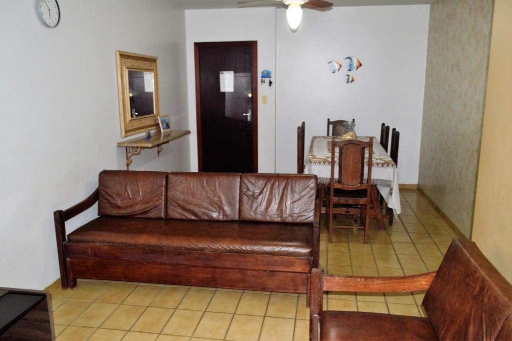 sala de estar con sofá de cuero marrón y mesa en Apartamento Di Cavalcanti, en Guarapari