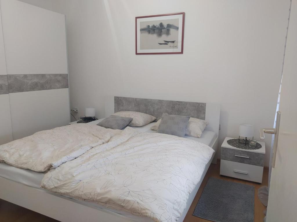 - une chambre avec un lit blanc et une photo sur le mur dans l'établissement Apartman Ana 1, à Valpovo