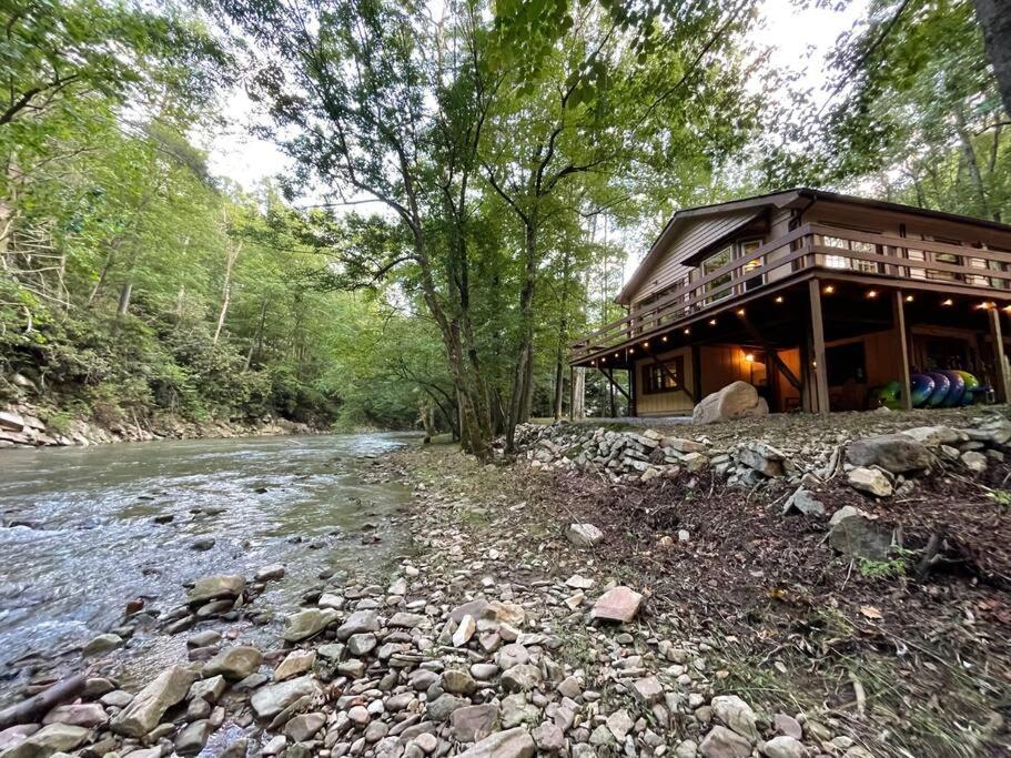 eine Blockhütte neben einem Fluss mit Bäumen in der Unterkunft Cozy Creekside cabin- 35m to Boone in Butler