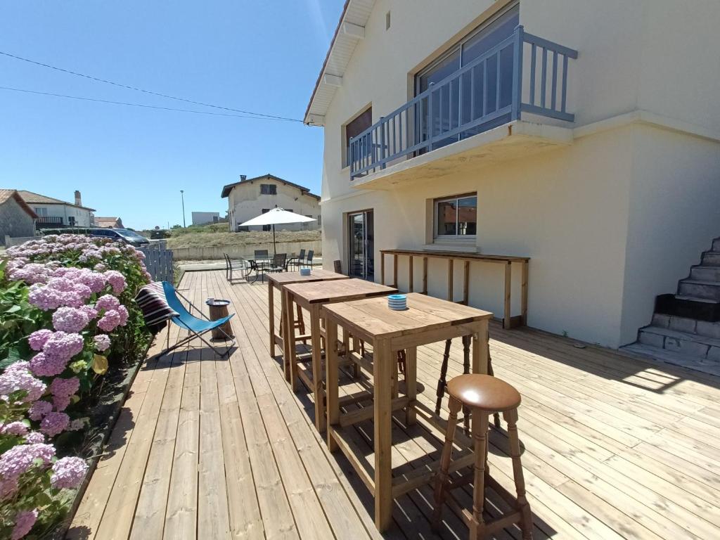 a wooden deck with tables and chairs on a house at Maison Mimizan plage in Mimizan