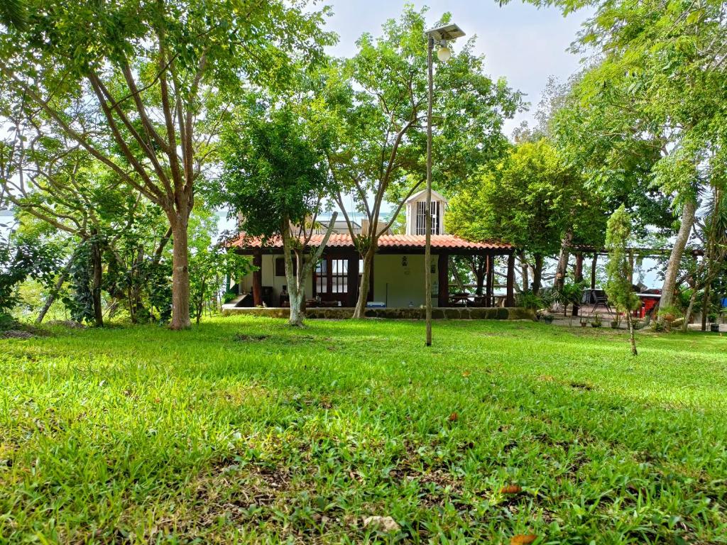 a house in the middle of a field with trees at Casa Agua Bacalar / Naajil Ha in Bacalar